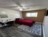Cozy bedroom with elegant wooden flooring, a chic red bedspread, and a stylish work desk, perfect for relaxation and productivity.