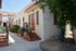 Charming apartment complex with classic stucco facade, lush greenery, and inviting red doors under a sunny blue sky.
