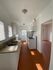 Bright galley kitchen featuring white cabinetry, granite countertops, and natural light from large windows.
