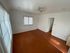 Bright apartment room featuring elegant hardwood floors, abundant natural light from large windows, and a stylish ceiling fan.