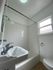 Bright and inviting bathroom with sleek white tiles, modern fixtures, and natural light from a window.