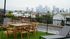 Chic rooftop patio with a wooden dining set and lounge chair, offering breathtaking cityscape views over a vibrant urban neighborhood.