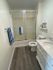 Elegant bathroom with modern glass-enclosed shower, marble countertop, and stylish wood flooring.