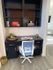 Chic home office nook featuring a sleek black desk, modern blue and white office chair, and decorative shelving with books and decor.