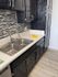 Modern kitchen with sleek black cabinets, stylish backsplash, and double stainless steel sink.