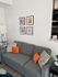 Chic living room with a gray sofa adorned with vibrant orange and patterned cushions, complemented by stylish framed artwork on the wall.