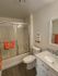 Bright and modern bathroom with elegant marble countertop, sleek shower doors, and vibrant orange accents for a refreshing and stylish look.