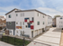 Modern apartment complex with sleek geometric design and individual garages, set in a bright and inviting neighborhood.