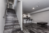 Sleek and modern apartment interior showcasing a stylish staircase, chic open-concept kitchen with bar stools, and elegant dark wood flooring.