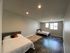 Spacious and bright bedroom with modern flooring, two comfortable beds, and ample natural light from large windows.