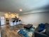 Modern open-concept living area with stylish kitchen featuring sleek stainless steel appliances, bar seating, and cozy lounge space with vibrant decor.