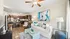 Bright open-concept living space featuring a stylish kitchen with dark wooden cabinets, cozy seating area with modern decor, and a vibrant abstract wall art.