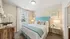 Cozy bedroom featuring a stylish turquoise headboard, elegant decor, and ample natural light through large windows.