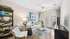 Bright and stylish living room with elegant decor, featuring a cozy sofa, glass coffee table, and vibrant artwork. French doors invite natural light, enhancing the inviting ambiance.