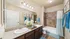 Elegant bathroom featuring dual sinks, modern lighting, and tasteful decor with seashell art and blue accents.