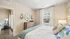 Inviting bedroom with natural light, featuring stylish decor, a rustic dresser, and cozy ambiance.
