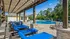 Charming outdoor pool area with luxurious blue chaise lounges under a rustic wooden pergola, perfect for relaxation and leisure.