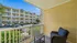 Charming apartment balcony with cozy seating overlooking a well-maintained building and parking area, offering a pleasant view and serene ambiance.