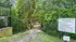Enchanting walkway leading into a lush, green dog park surrounded by trees, with welcoming sign and clear rules displayed at the entrance.