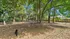 Spacious fenced backyard shaded by lush trees, offering a serene and natural retreat perfect for relaxation.