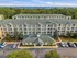 Charming coastal apartment complex with lush greenery, ample parking, and breathtaking ocean views in the distance.