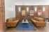 Chic apartment lounge featuring two vintage leather sofas, a sleek coffee table, vibrant modern artwork, and ambient wall lighting on a stylish brick backdrop.