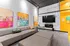 Vibrant living room featuring modern artwork, a spacious sectional sofa, and a sleek entertainment setup with a large TV and stylish fireplace.