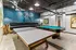 Chic game room showcasing a modern ping-pong and pool table, with industrial decor and a cozy seating area.