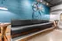Chic industrial-style space featuring a modern black leather sofa, teal brick wall, and vintage bicycle decor.