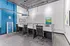 Modern and vibrant workspace featuring sleek cubicles with stylish black chairs, colorful artwork, and a bright blue accent wall, perfect for productive co-working.