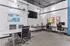 Modern office space with sleek desks, ergonomic chairs, abstract artwork, and a mounted flat-screen TV, offering a vibrant and functional workspace.