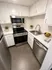 Modern kitchen with sleek stainless steel appliances, white cabinetry, and stylish tile flooring, ideal for culinary enthusiasts.