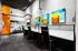 Modern office space with sleek black chairs, vibrant abstract art, and a bold orange accent wall.