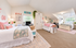 Charming shared bedroom with vibrant decor, featuring two cozy beds, cheerful wall art, and ample storage in a bright, sunlit space.