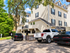 Charming apartment building with elegant colonial-inspired architecture, surrounded by lush greenery and convenient parking facilities.