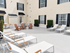 Charming outdoor patio with elegant lounge chairs, wooden seating area, and lush greenery for a relaxing ambiance.