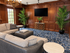 Elegant living room featuring rich wood paneling, plush seating, lush green plants, and a stylish chandelier.