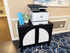 Elegant lobby corner featuring a modern printer on a stylish cabinet, enhanced by a floral design and fresh flower arrangement, against charming wallpaper and contemporary carpet.