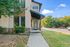 Modern apartment entrance with sleek design, large windows, and lush greenery in a vibrant neighborhood.