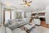 Modern open-concept living room with cozy sofas, elegant ceiling fan, and stylish kitchen with dark cabinetry and sleek appliances.