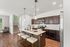 Chic open-concept kitchen with modern dark wood cabinets, granite island, and sleek stainless steel appliances, accented by elegant pendant lighting.