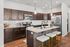 Modern kitchen featuring elegant dark wood cabinets, a stylish granite island with seating, and stainless steel appliances, offering a perfect blend of functionality and design.
