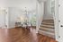 Charming dining area with elegant chandelier, modern furniture, and inviting staircase, perfect for cozy gatherings.