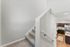Modern staircase leading to a bright, spacious kitchen with wooden cabinetry and sleek appliances.