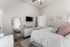 Cozy bedroom with modern decor, featuring a soft bed with plush pillows, a sleek dresser, and a mounted TV complementing framed artwork.