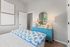 Charming bedroom with a bright teal dresser, elegant mirror, and vibrant decor, creating a cozy and inviting atmosphere.