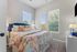 Charming bedroom bathed in natural light, featuring a plush blue headboard, vibrant floral bedding, and elegant decor.
