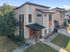 Modern two-story apartment with a sleek exterior design, surrounded by lush greenery, offering a prime location and contemporary architecture.