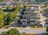 Aerial view of modern apartment complex surrounded by lush greenery, showcasing ample parking and easy road access.