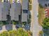Aerial view of modern residential community featuring neatly arranged townhouses with spacious driveways, surrounded by greenery and a quiet street.